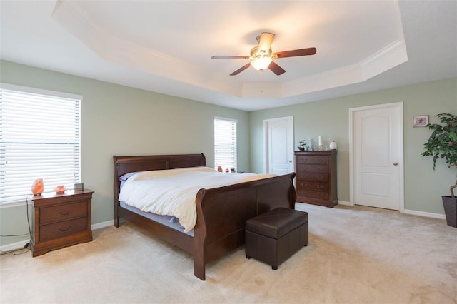 bedroom featuring crown molding, light carpet, a ceiling fan, baseboards, and a tray ceiling