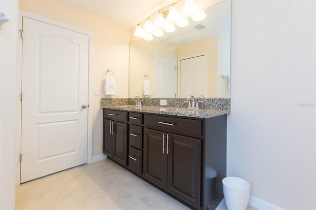 bathroom featuring a sink, baseboards, tile patterned flooring, and double vanity