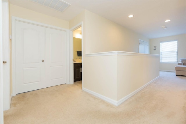 corridor with baseboards, light carpet, recessed lighting, and visible vents