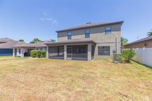 back of house with a sunroom, a lawn, stucco siding, and fence