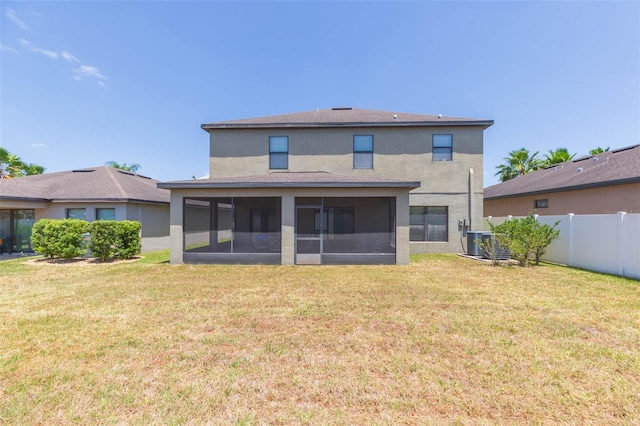 rear view of property featuring a lawn, fence, a sunroom, and stucco siding