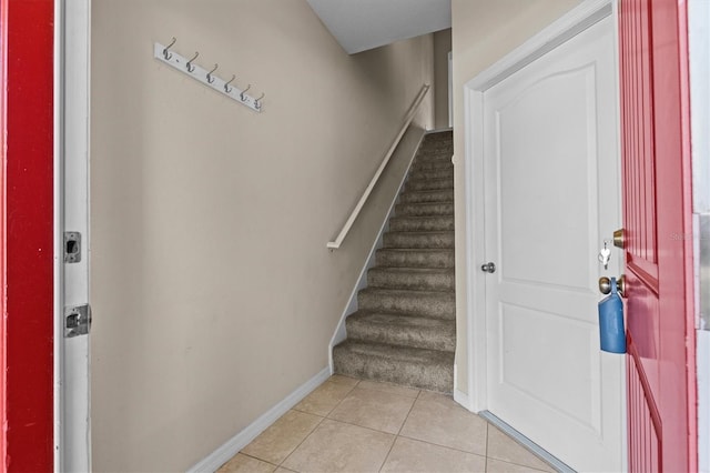 entrance foyer with stairway, light tile patterned floors, and baseboards
