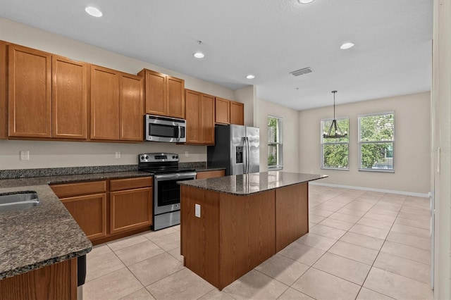 kitchen featuring stainless steel appliances, a kitchen island, light tile patterned floors, brown cabinets, and recessed lighting