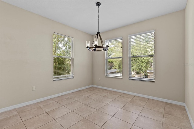 unfurnished room with light tile patterned floors, plenty of natural light, and a chandelier