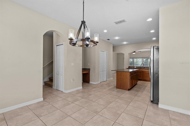 kitchen featuring arched walkways, freestanding refrigerator, a chandelier, dark countertops, and recessed lighting