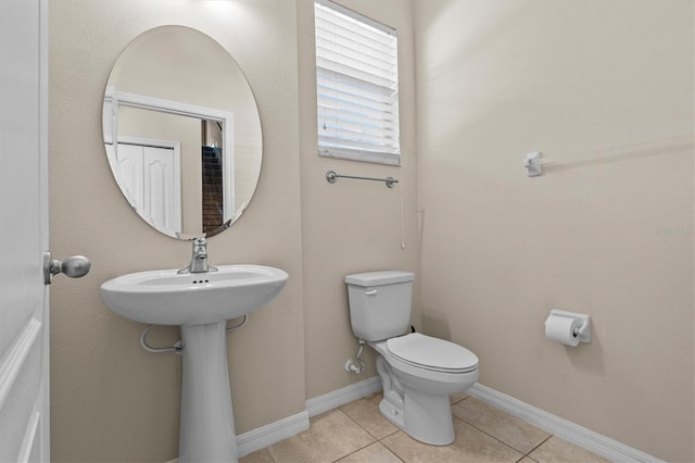 bathroom with toilet, tile patterned floors, and baseboards