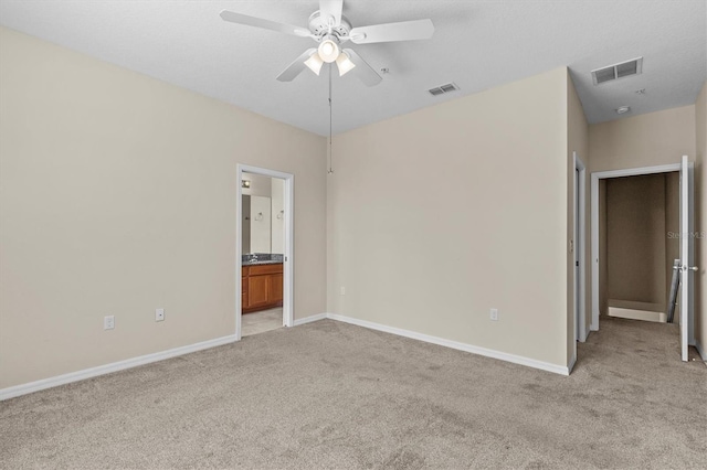 unfurnished bedroom with light colored carpet, baseboards, and ensuite bathroom
