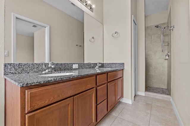 full bath with tiled shower, tile patterned floors, double vanity, and baseboards