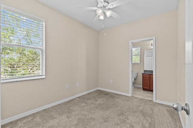 unfurnished bedroom featuring light carpet, baseboards, and connected bathroom
