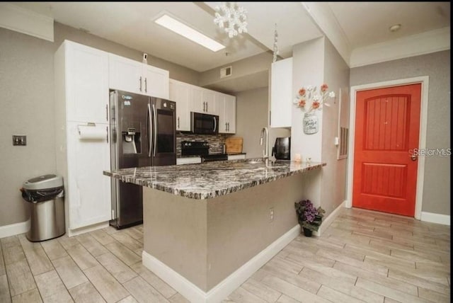 kitchen with light wood-style floors, white cabinets, black appliances, and dark stone countertops