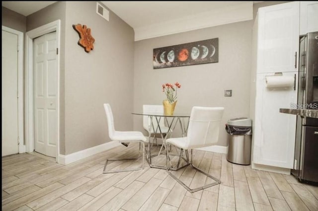 dining room with visible vents, light wood finished floors, and baseboards