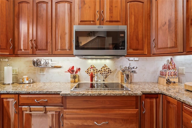 7353 Dogwood Cres, Spring Hill, FL 34607 - kitchen with stainless steel microwave, black electric cooktop, light stone counters, and decorative backsplash