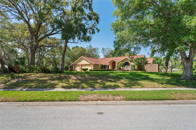 7353 Dogwood Cres, Spring Hill, FL 34607 - view of front of house featuring an attached garage, a front lawn, and stucco siding