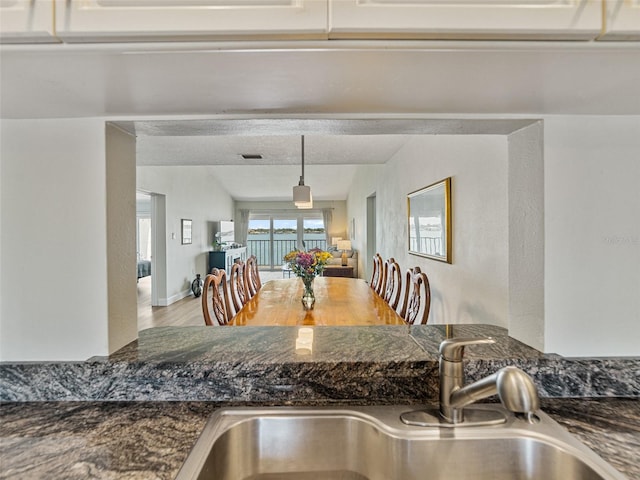 kitchen with a sink, dark stone countertops, and wood finished floors