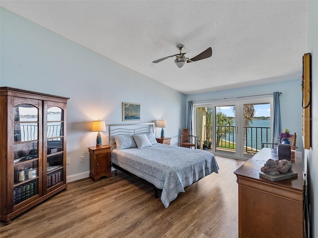 bedroom with access to outside, vaulted ceiling, and wood finished floors