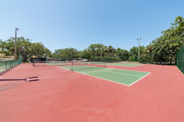 view of tennis court with community basketball court and fence