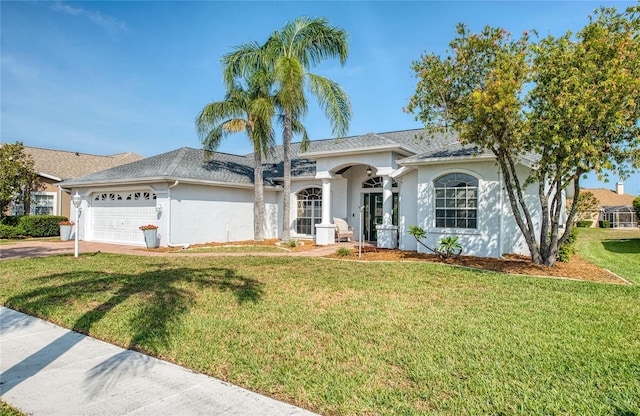 ranch-style home featuring an attached garage, stucco siding, a front lawn, and driveway