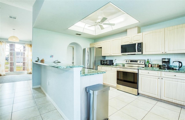 kitchen featuring appliances with stainless steel finishes, light tile patterned floors, light stone countertops, and arched walkways