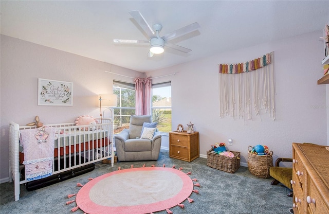 bedroom featuring carpet flooring, a nursery area, ceiling fan, and baseboards