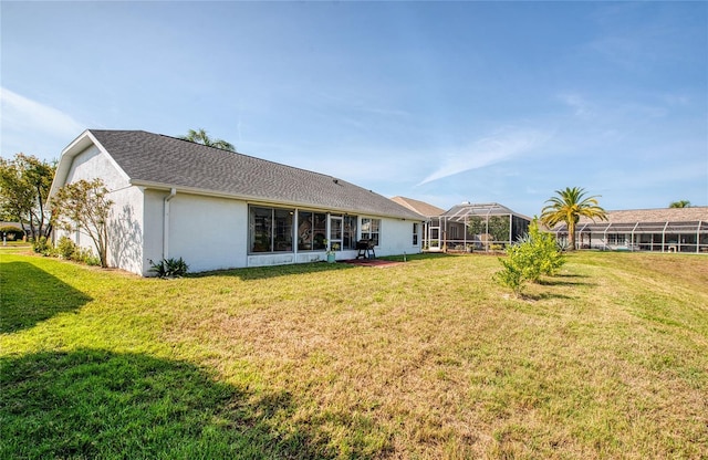 back of property featuring a lawn and stucco siding
