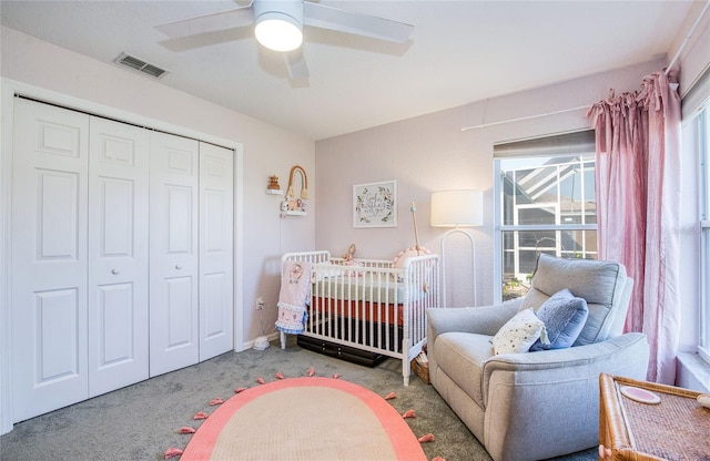 carpeted bedroom with a closet, a nursery area, and a ceiling fan