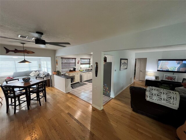 dining room with visible vents, a textured ceiling, light wood-style flooring, and ceiling fan