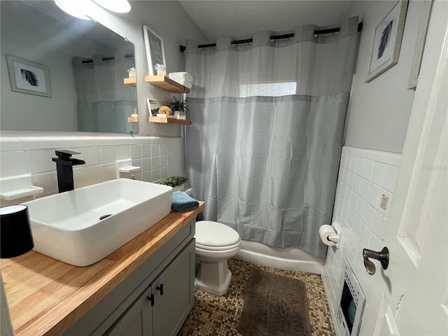 full bathroom featuring tile patterned flooring, vanity, toilet, shower / bathtub combination with curtain, and tile walls