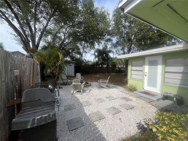 view of patio featuring grilling area, an outdoor structure, a fenced backyard, and a storage unit