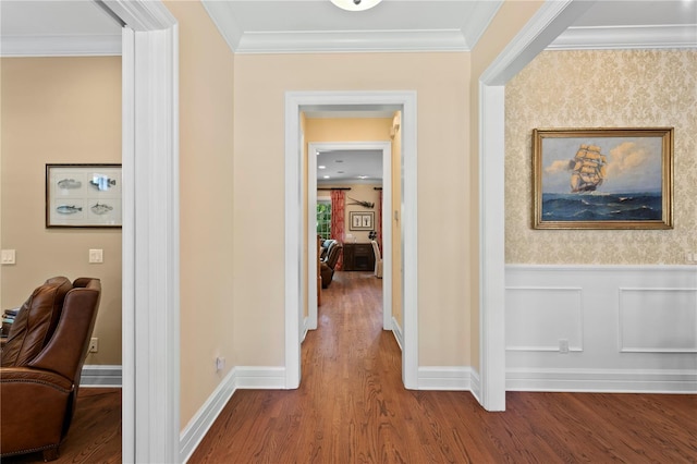 hallway with wood finished floors, ornamental molding, wainscoting, and baseboards