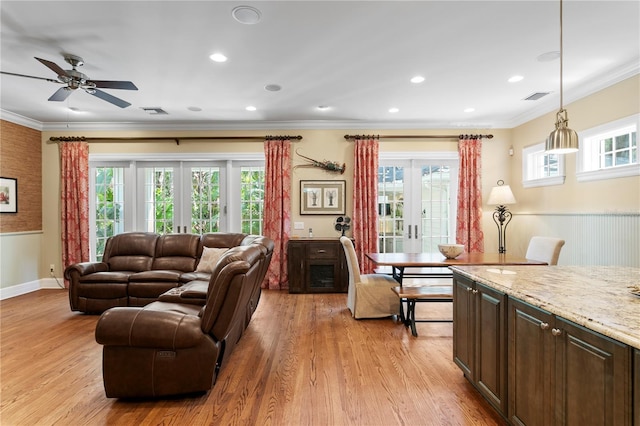 living room with light wood-style floors, ornamental molding, a ceiling fan, french doors, and baseboards