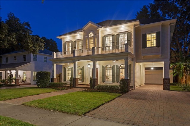 view of front facade featuring a balcony, decorative driveway, a porch, an attached garage, and french doors