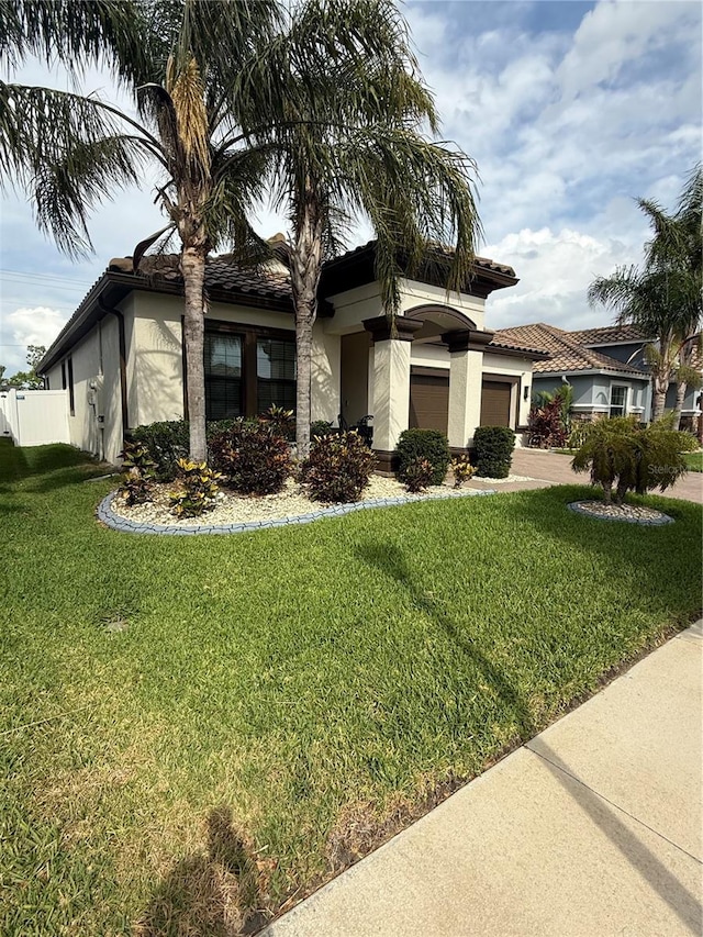 ranch-style house with an attached garage, stucco siding, a front yard, and concrete driveway