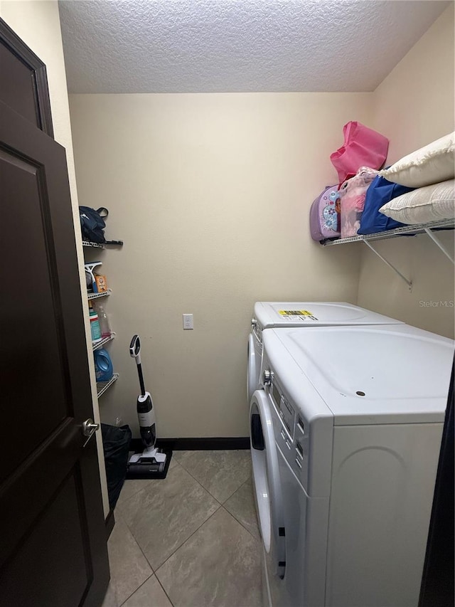 clothes washing area featuring light tile patterned floors, a textured ceiling, laundry area, and independent washer and dryer