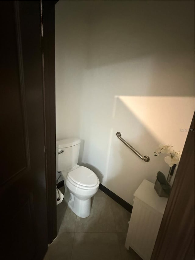 half bathroom with baseboards, tile patterned floors, and toilet