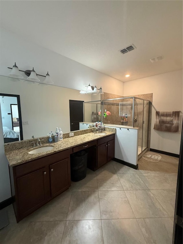 ensuite bathroom with visible vents, a sink, double vanity, and a shower stall