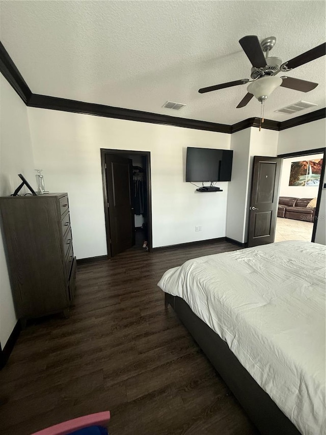 bedroom featuring baseboards, ornamental molding, wood finished floors, and visible vents