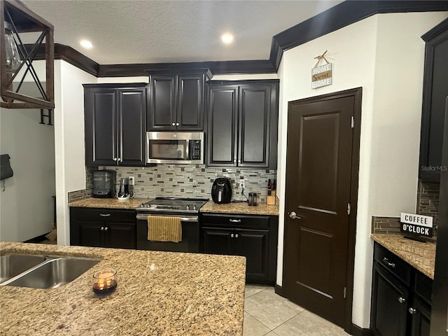 kitchen with dark cabinets, appliances with stainless steel finishes, backsplash, and light tile patterned flooring