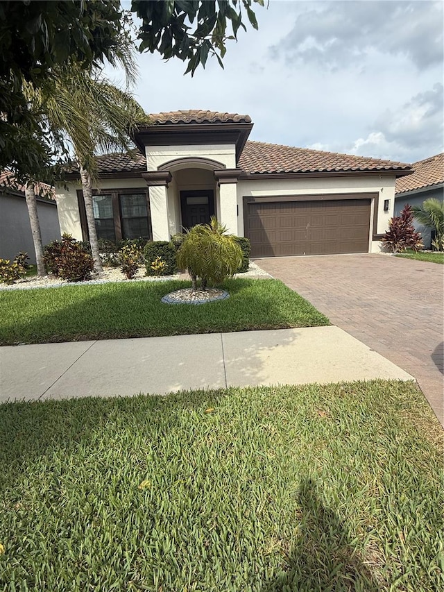 mediterranean / spanish-style house with stucco siding, decorative driveway, a tile roof, and a garage