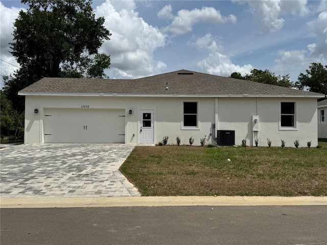 single story home with a garage, stucco siding, central air condition unit, a front lawn, and decorative driveway