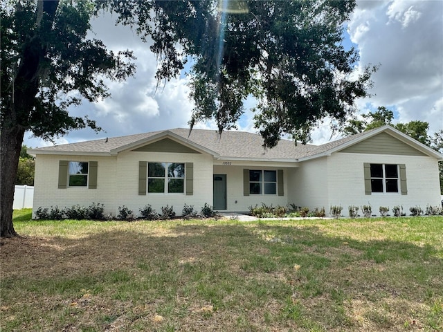 single story home with roof with shingles, fence, a front lawn, and brick siding