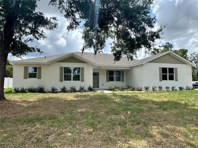 ranch-style house featuring brick siding, a front lawn, and fence