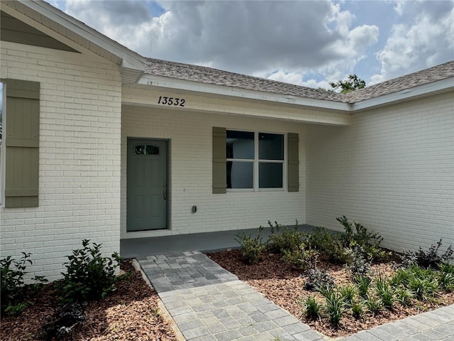 property entrance with a porch and brick siding