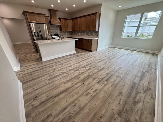 kitchen with recessed lighting, a sink, custom range hood, open floor plan, and backsplash