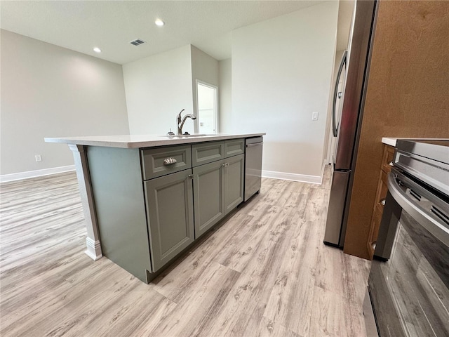 kitchen featuring stainless steel appliances, light wood-type flooring, gray cabinets, baseboards, and visible vents