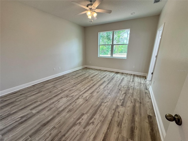 spare room featuring ceiling fan, a textured ceiling, baseboards, and wood finished floors