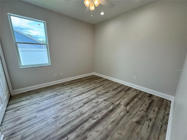 empty room with wood finished floors, baseboards, ceiling fan, and recessed lighting