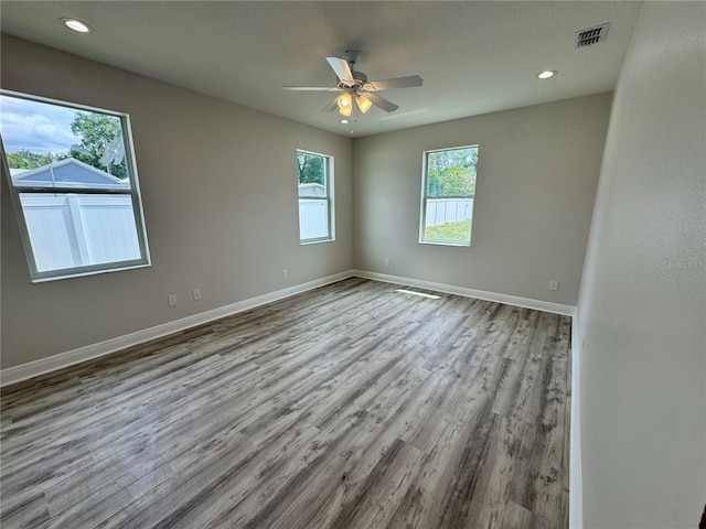 empty room featuring baseboards, a ceiling fan, visible vents, and wood finished floors