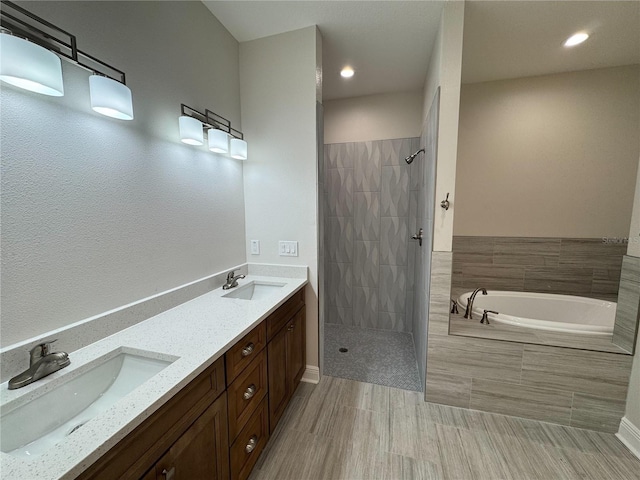 bathroom with a garden tub, baseboards, tiled shower, and a sink