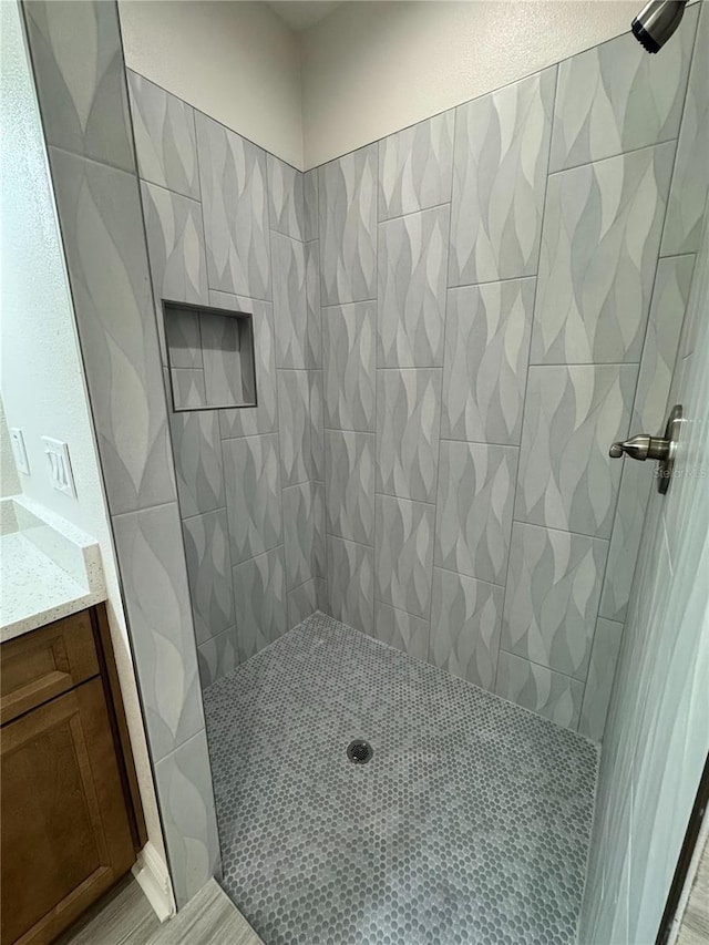 bathroom with vanity and a tile shower