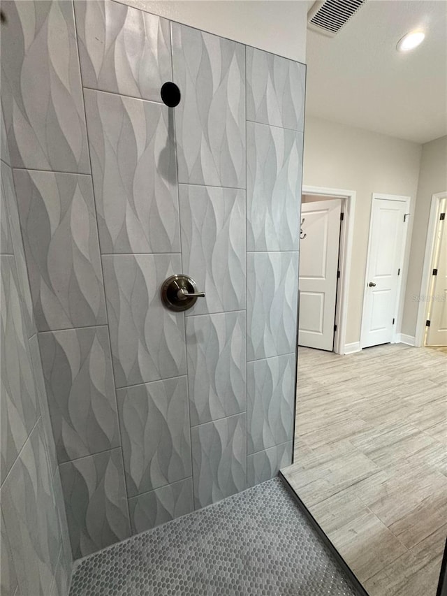 full bathroom with recessed lighting, tiled shower, and visible vents